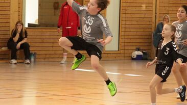 Jugendhandball Spieler beim Sprungwurf während eines Spiels in der Sporthalle, dynamische Angriffsszene im Nachwuchs-Handballverein