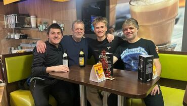 Vier Vereinsmitglieder sitzen gemeinsam am Tisch in einem Café oder Vereinslokal, geselliges Beisammensein nach einem Spiel oder Training