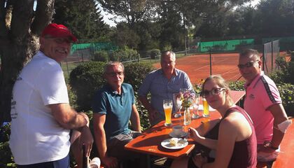 Menschen sitzen um einen Biertisch mit Getränken auf dem Tisch