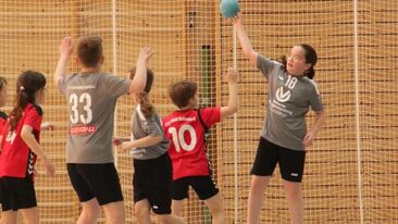 Jugendhandball Spielerin beim Torwurf im Spiel, mehrere Kinder in der Sporthalle während einer Spielsituation im Nachwuchs-Handballverein