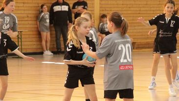Zwei Jugendhandball Spielerinnen im direkten Duell mit Ball in der Sporthalle, Spielsituation im Nachwuchs-Handballverein