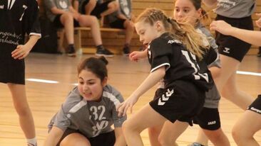 Mehrere Kinder im Jugendhandball kämpfen um den Ball in der Sporthalle, intensive Spielsituation im Nachwuchs-Handballverein