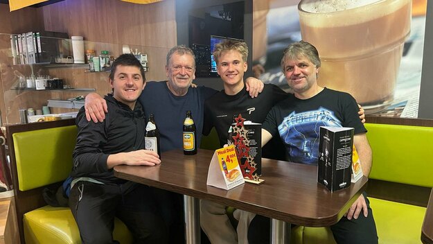 Vier Vereinsmitglieder sitzen gemeinsam am Tisch in einem Café oder Vereinslokal, geselliges Beisammensein nach einem Spiel oder Training